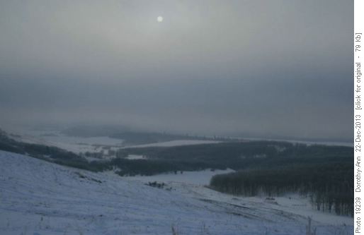 A weak sun looks down on mist-shrouded fields