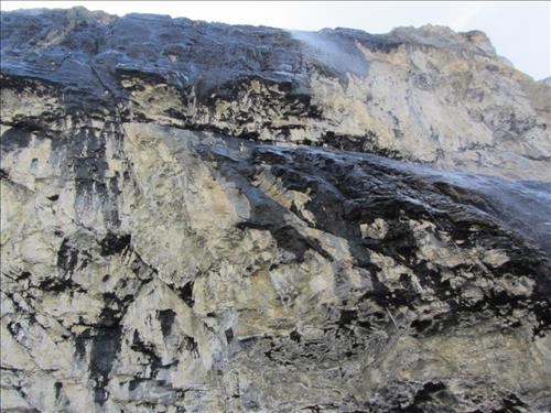 Looking straight up the cliff at meltwater raining over the edge (with black lichen?)