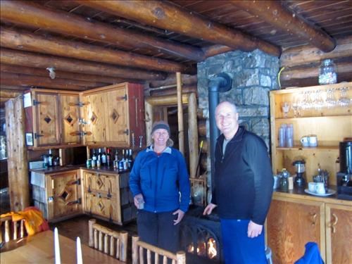 {184 Kim Kem} and {1960 Rich Hedg} warming up by the stove at Skoki lodge
