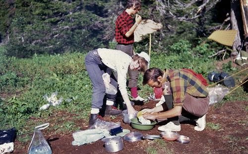 Daphne Smith and Brian Crummy doing dishes, Paul Jepson breaking camp, Glacier USA 1972