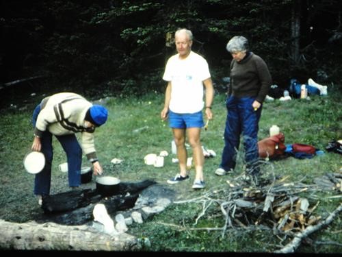 {0 Richard Jull} cooks dinner watched by {265 Alistair DesMoulins} and {314 Gail DesMoulins} during a backpack in Montana, USA