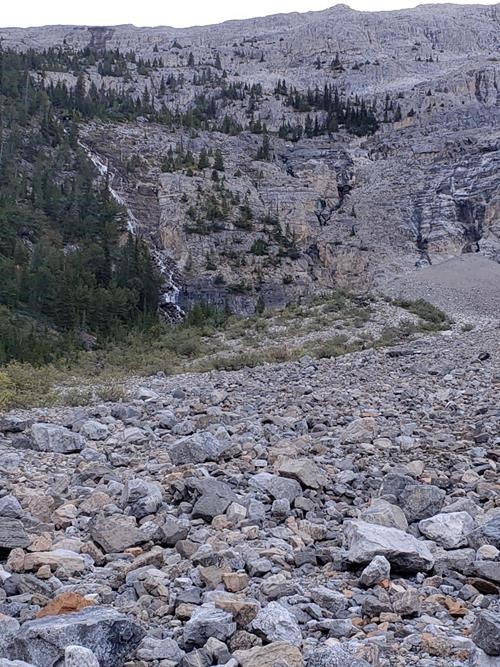 The route up the headwall goes up the sparsely treed slope to the right of the waterfall