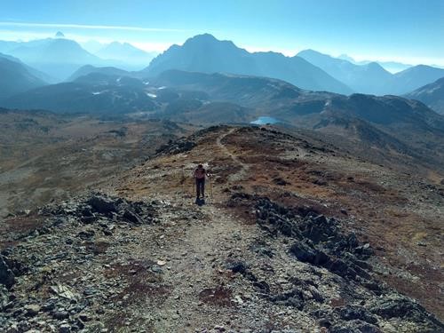 {1314 Barb Brun} toils up to high point; smoke wreathed Assiniboine & the Monarch in the distance