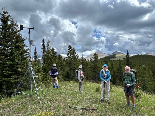 Group posing by a weather gadget close to the third peak