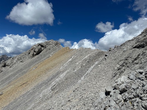 The scree run descent from the false summit, on the gold/brown scree