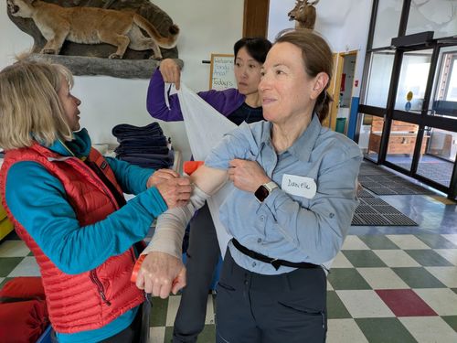 Barbara and Lilianne practice broken arm splinting and making a sling on Danielle