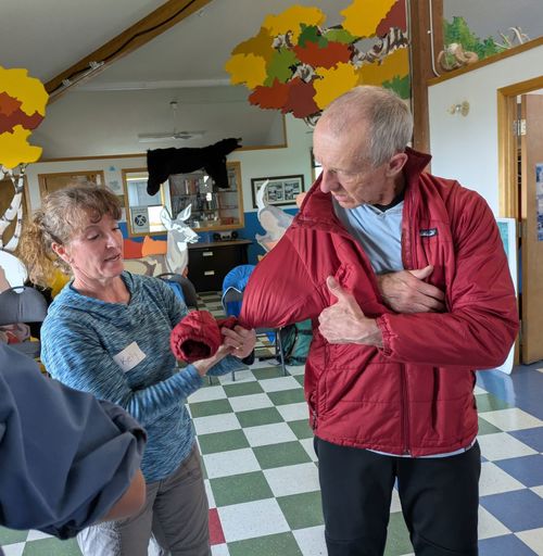 Using a coat for a sling as demonstrated by teacher Kelly on Marcus